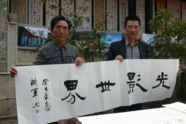璧山书法家为印江摄影家赠书“光影世界”。